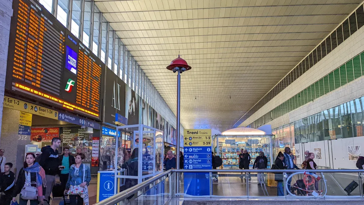 The departures board and main hall of Roma Termini station, seen on the Rome to Florence train