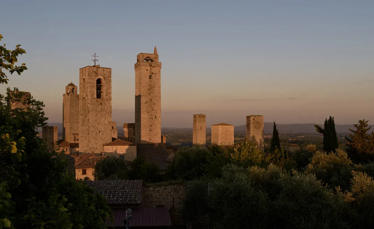 The medieval towers of San Gimignano at sunset above the Tuscan hills, seen on a Florence and Tuscany day trip from Rome